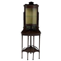 Edwardian mahogany floor-standing corner cabinet, cylinder glazed door above mirror backed shelf, the lower tier with fretwork back, on leaf carved and reeded tapering supports 