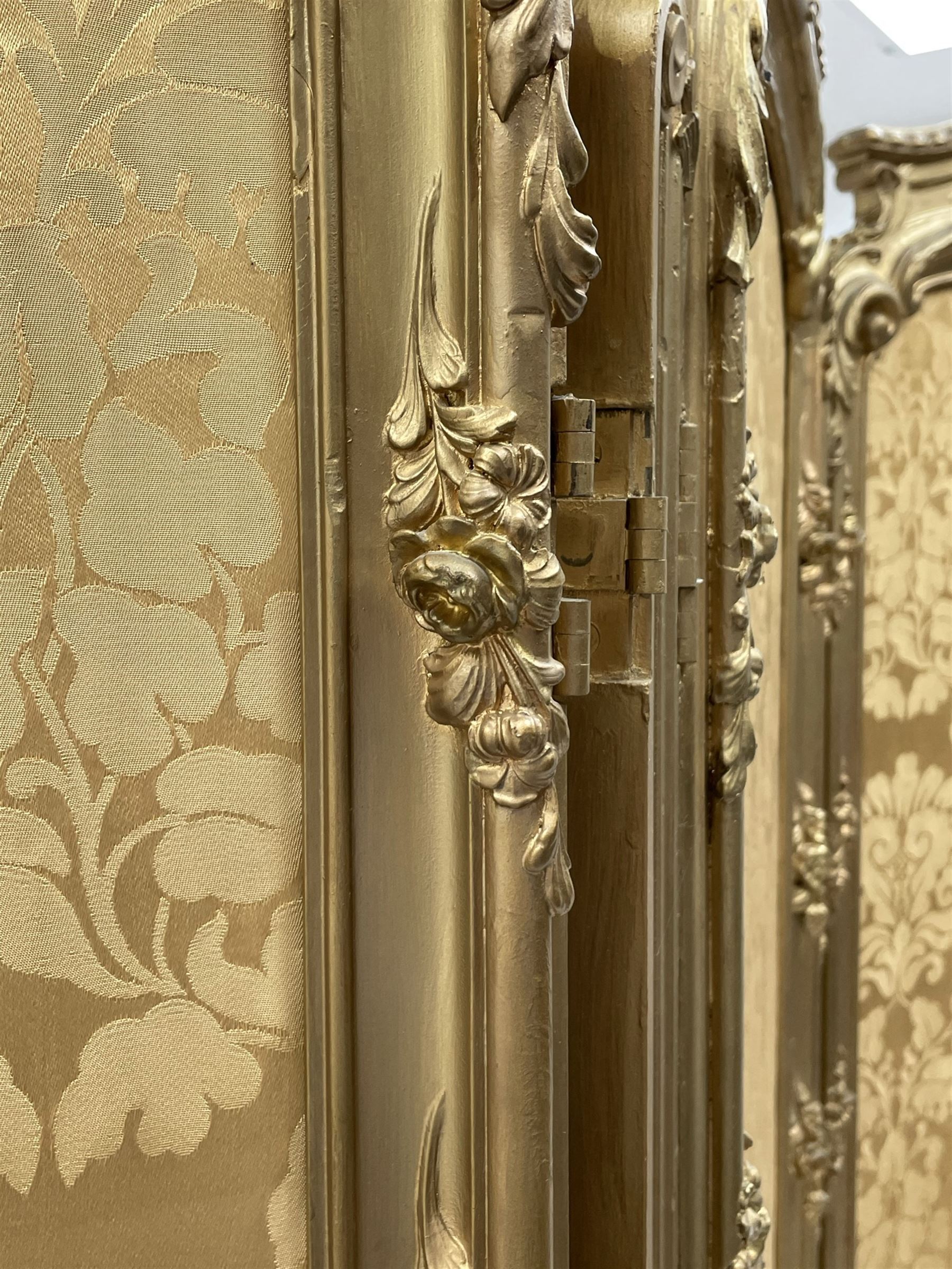 Late 19th/early 20th century French Rococo style gilt wood and gesso dressing screen, four double hinged panels, each with shaped cresting rail over shell and floral frieze, moulded frame with flower head and scroll decoration, acanthus leaf cabriole supports with castors, upholstered in gold Damask fabric