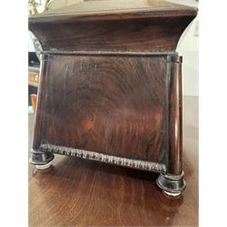 Early 19th century rosewood and brass inlaid tea caddy, of sarcophagus form, the front and hinged opening cover inlaid with brass scrolling panels, opening to reveal a compartmented interior with twin removable boxes with conforming inlaid brass detail to the hinged covers and zinc lining to the interiors, flanking a later glass mixing bowl, the whole upon four turned cylindrical feet, H21cm W36cm D20cm