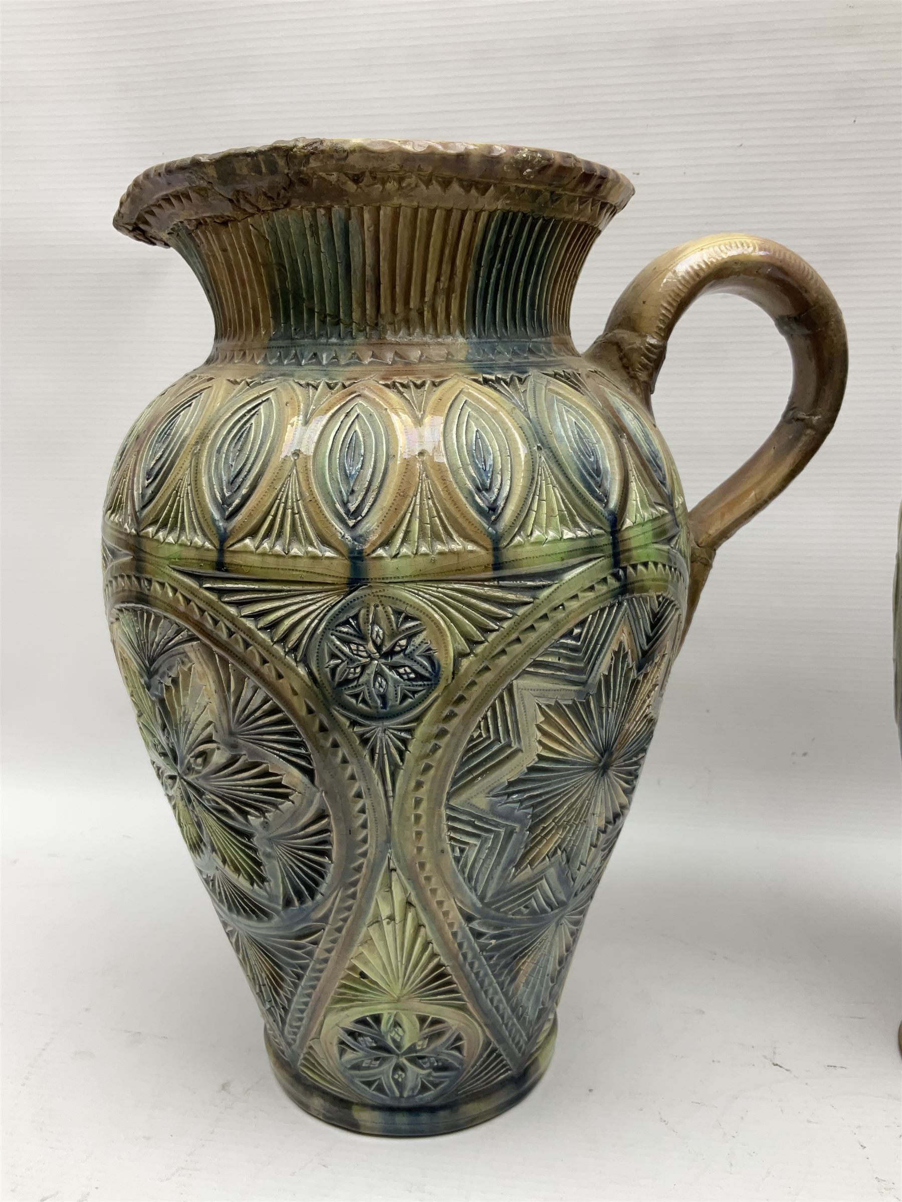 Early 20th century Royal Doulton stoneware vase, decorated with a stylized floral design below a wavy rim, monogrammed B.N, possibly for Bessie Newbery, H28cm, together with an early 20th century glazed jug, heavily carved throughout (2)