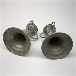 A pair of German pewter candlesticks, the circular bases with applied cabouchons, leading to a plannished tapering stem, and socket with three curved handles, each marked beneath Germany, H11cm. 