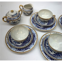 A Japanese eggshell porcelain teaset, comprising six teacups each with Geisha lithophane panel, six saucers, six side plates, teapot with woven carry handle, twin handled sucrier and milk jug, each decorated with blue floral and peacock pattern and heightened with gilt. 