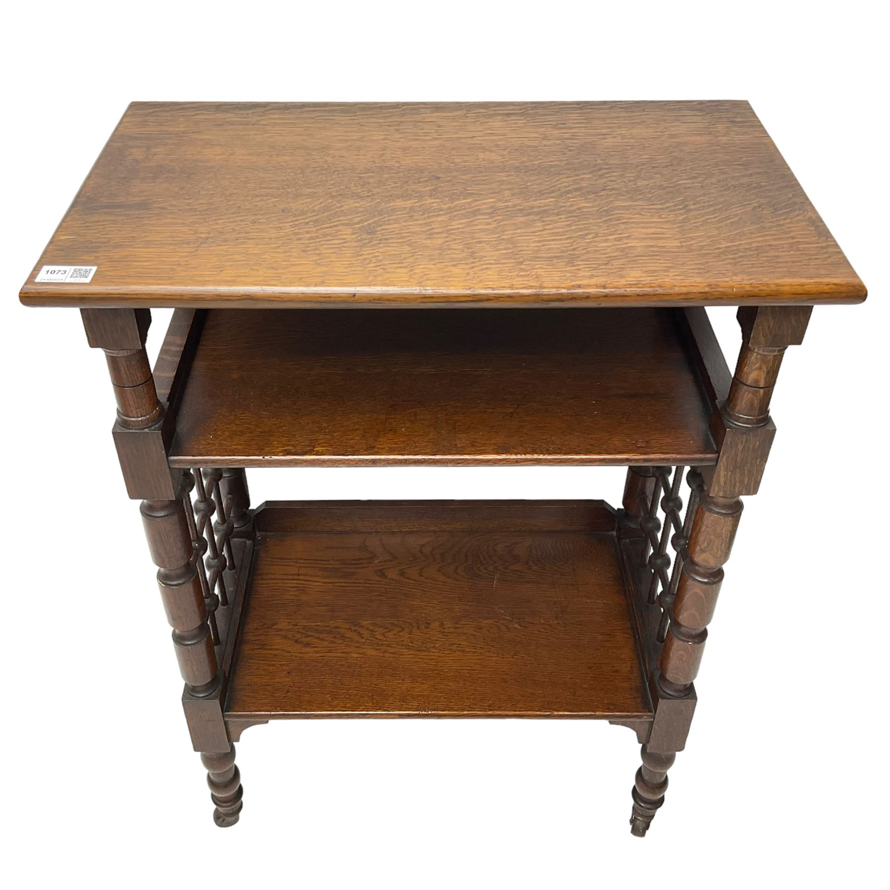 Late 19th century oak three-tier stand or bookcase, on turned supports with lattice sides, on turned feet with castors