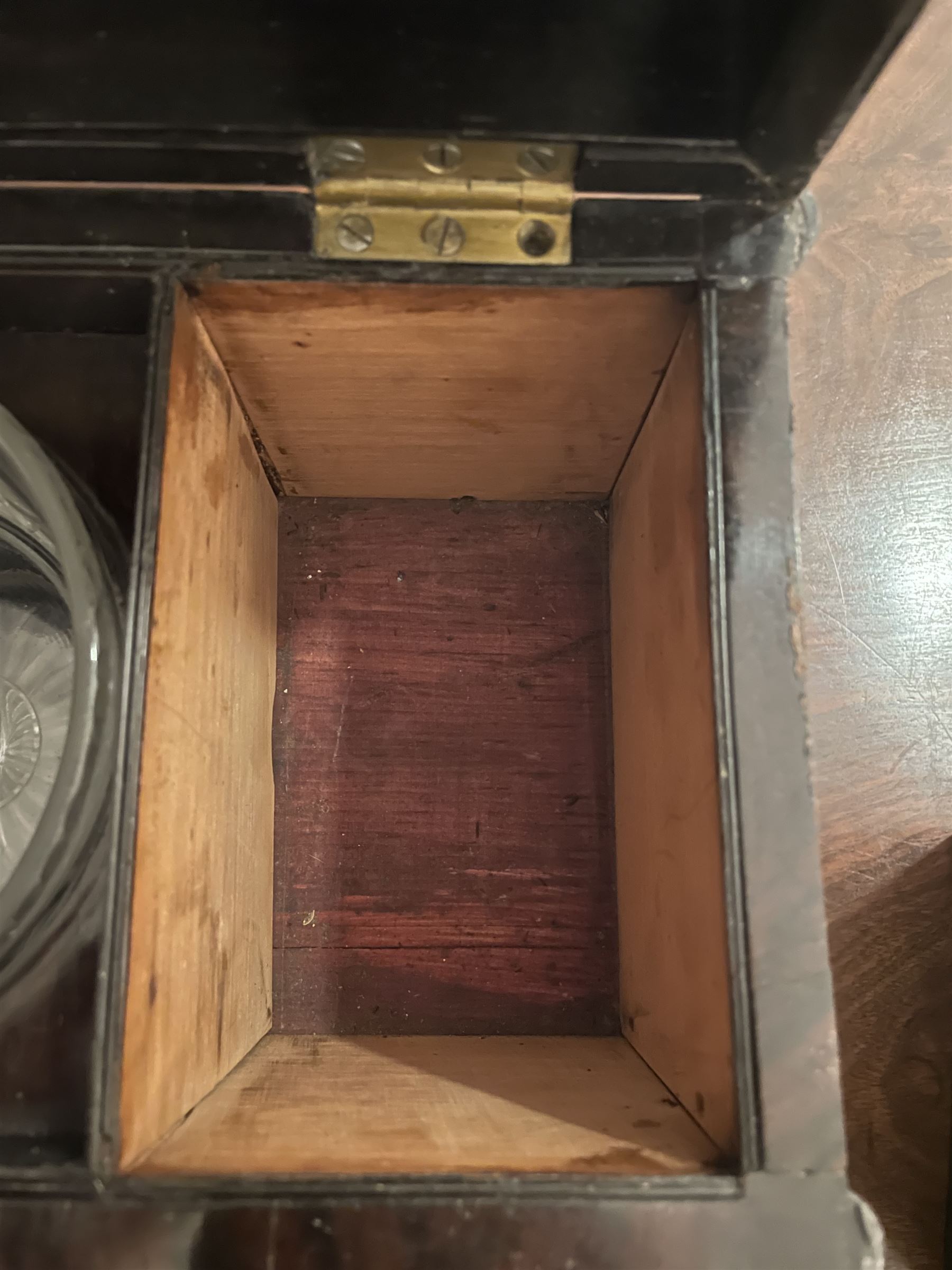 Early 19th century rosewood and brass inlaid tea caddy, of sarcophagus form, the front and hinged opening cover inlaid with brass scrolling panels, opening to reveal a compartmented interior with twin removable boxes with conforming inlaid brass detail to the hinged covers and zinc lining to the interiors, flanking a later glass mixing bowl, the whole upon four turned cylindrical feet, H21cm W36cm D20cm