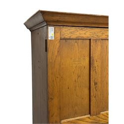 The North of England School Furnishing Company Limited Darlington - early 20th century oak school cupboard, projecting moulded cornice over two panelled doors, fitted with shelves, on chamfered plinth base 