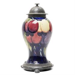 William Moorcroft for Liberty Wisteria pattern baluster vase on a dark blue ground with planished domed pewter cover and collar on a pewter stand marked Tudric Moorcroft 01308 Overall height 21cm