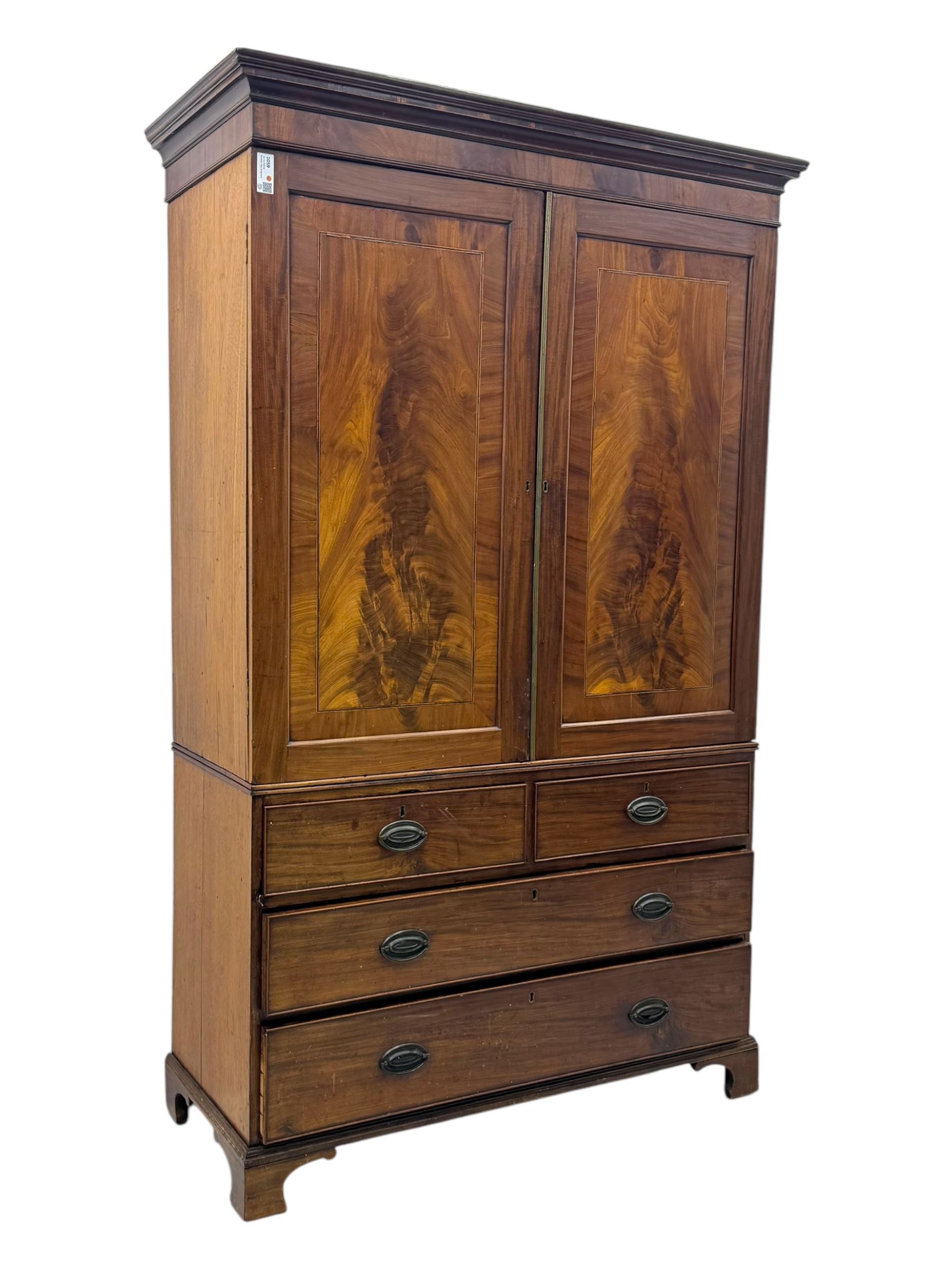 Early 19th century mahogany linen press cupboard, projecting moulded cornice over figured frieze, two panelled doors enclosing shelves, fitted with two short and two long cock-beaded drawers, on bracket feet 
