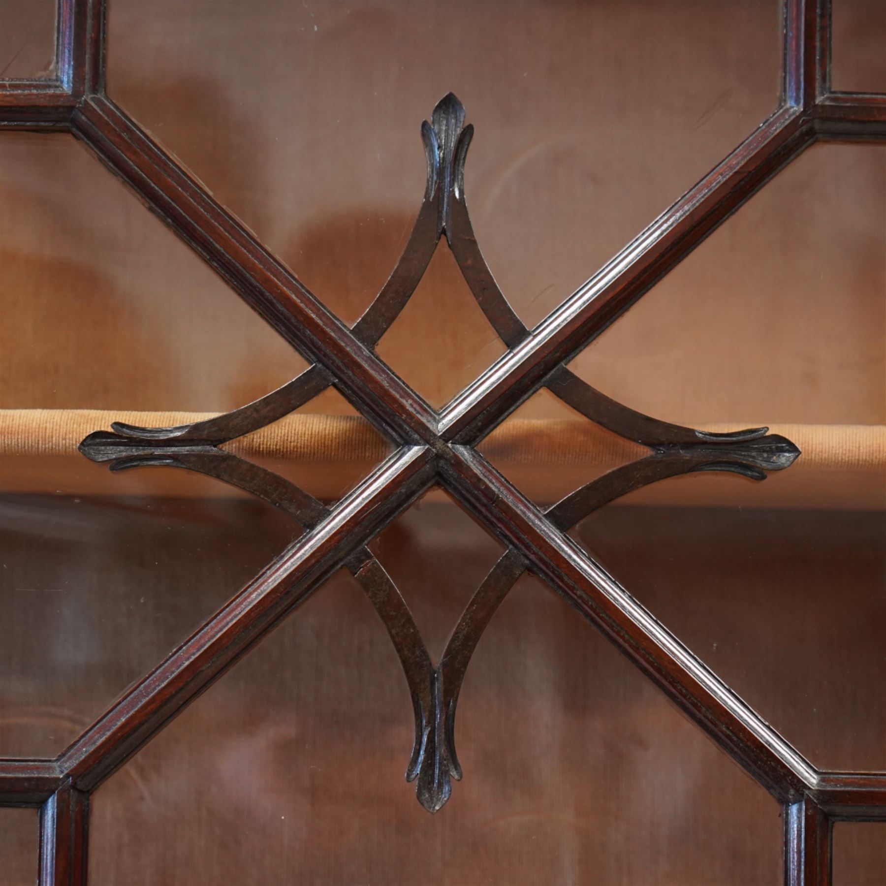 Large George III mahogany bookcase display cabinet, pierced swan neck pediment with floral head roundels over dentil and arcade frieze, enclosed by two geometric astragal glazed doors with lozenge motifs, the lined interior fitted with three shelves, gadrooned lower rail over acanthus carved cabriole supports with ball and claw feet 
