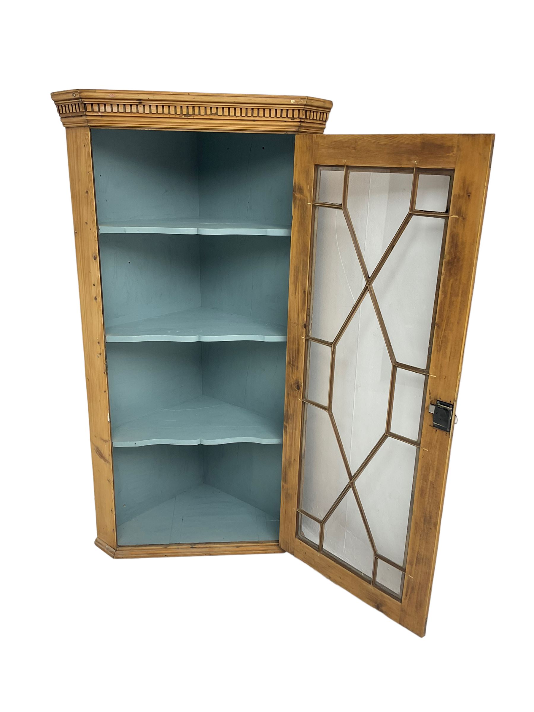 Early 19th century pine corner cabinet, projecting dentil cornice over astragal glazed door