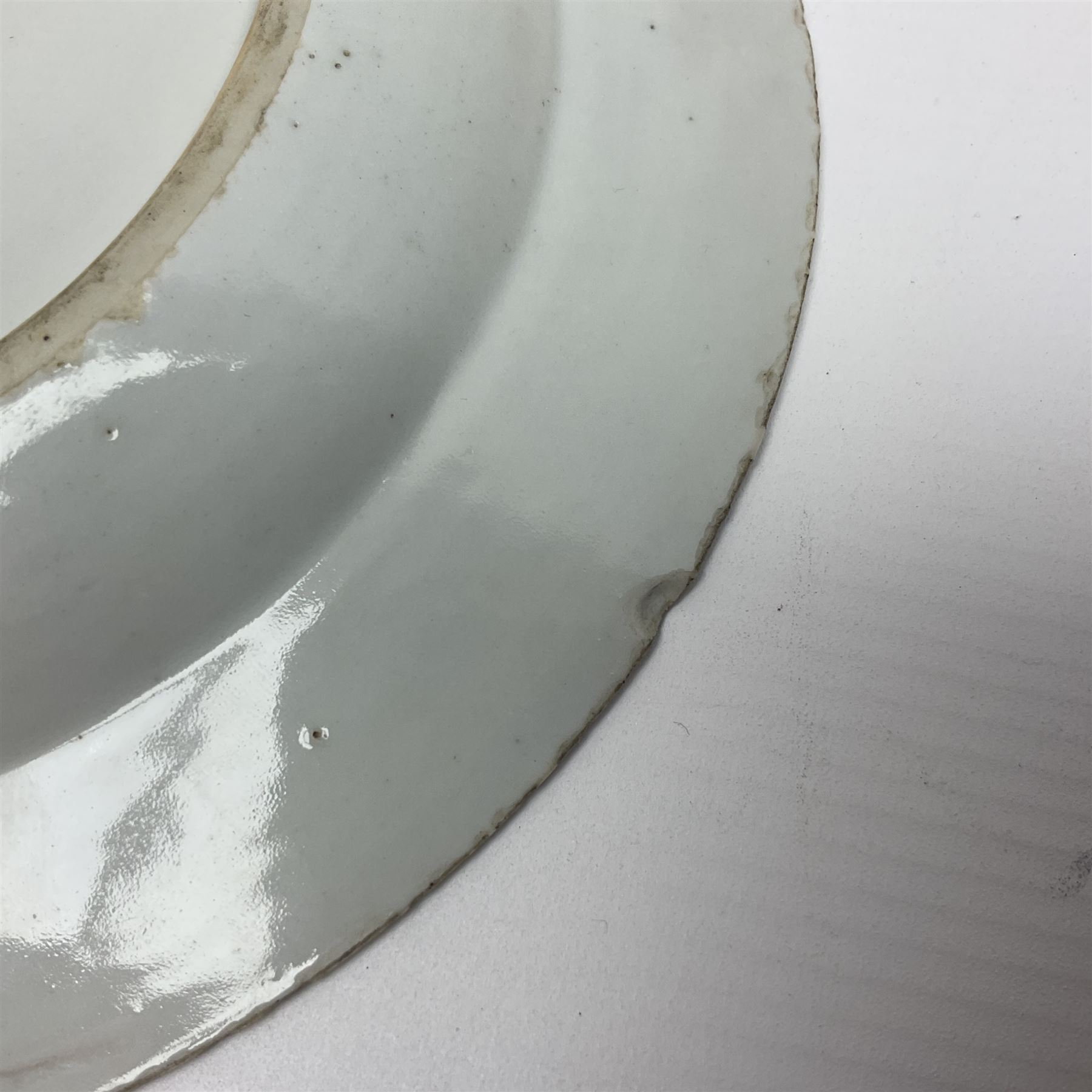 Three 18th century Chinese Famille Rose plates, the first example enamelled with blossoming peonies, rockwork and fence, the other two examples of similar design, decorated with blossoming peonies and sprigs within shaped inner borders, each approximately D23cm