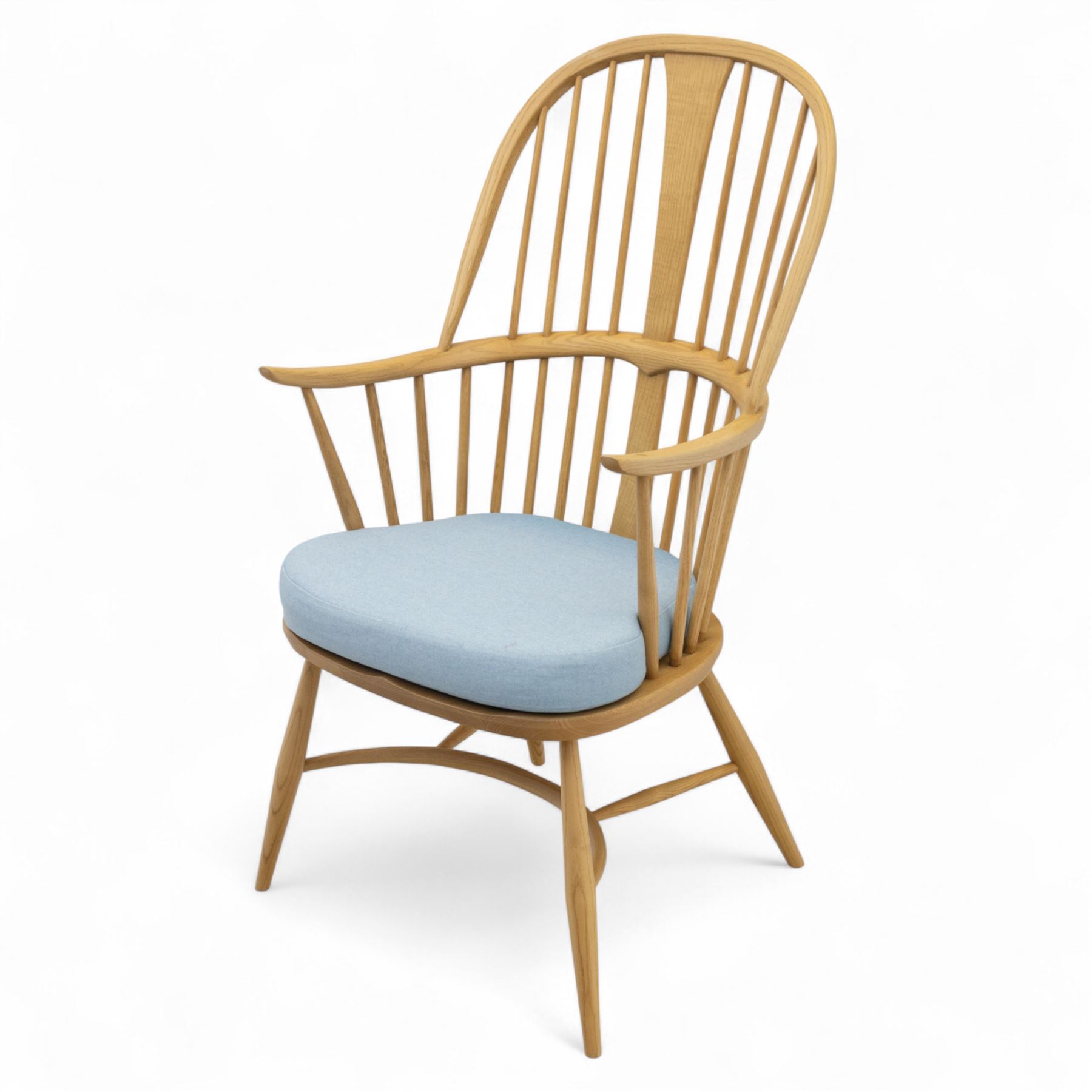 Ercol - ‘Chairmakers’ armchair, of traditional Windsor form in light ash, featuring a hoop back with four spindles and central splat, curved arms and turned supports, dished seat with upholstered blue cushion