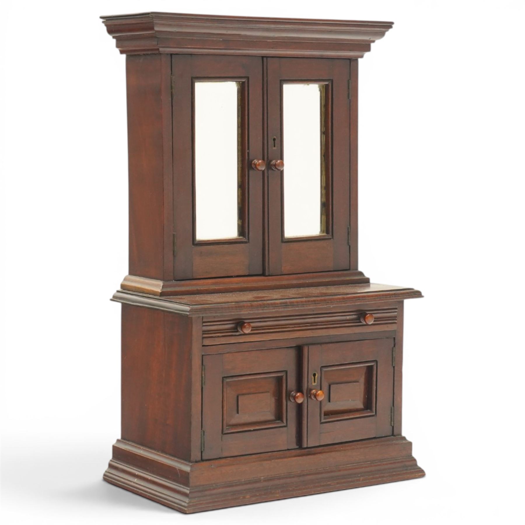 Miniature Victorian mahogany apprentice's cabinet-on-chest, the projecting cavetto cornice over two doors with bevelled mirror plates, the base fitted with single reeded frieze drawer over a panelled cupboard, on stepped plinth base