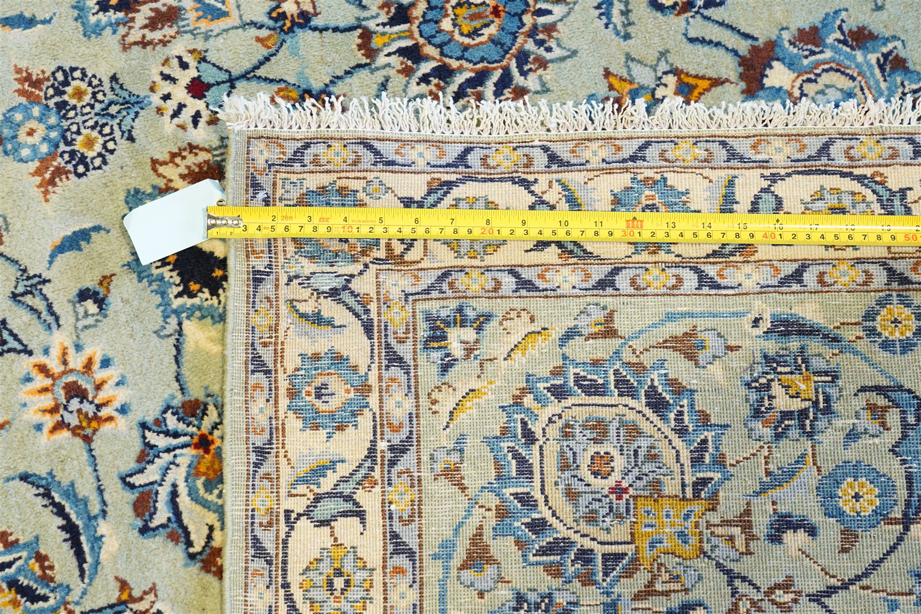 Central Persian Kashan hand-knotted carpet, pale blue field decorated with an all-over scrolling floral vine design incorporating stylized palmettes, rosettes and foliate sprays enclosed by a conforming floral vine border between multiple guard stripes, with cotton fringe ends 