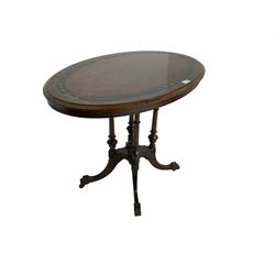 Late 19th century oval walnut tilt-top loo table, figured quarter matched veneer with ebonised banding and foliate decoration, raised on platform base supported by four quadruple turned and fluted pillars, splayed carved supports with brass castors