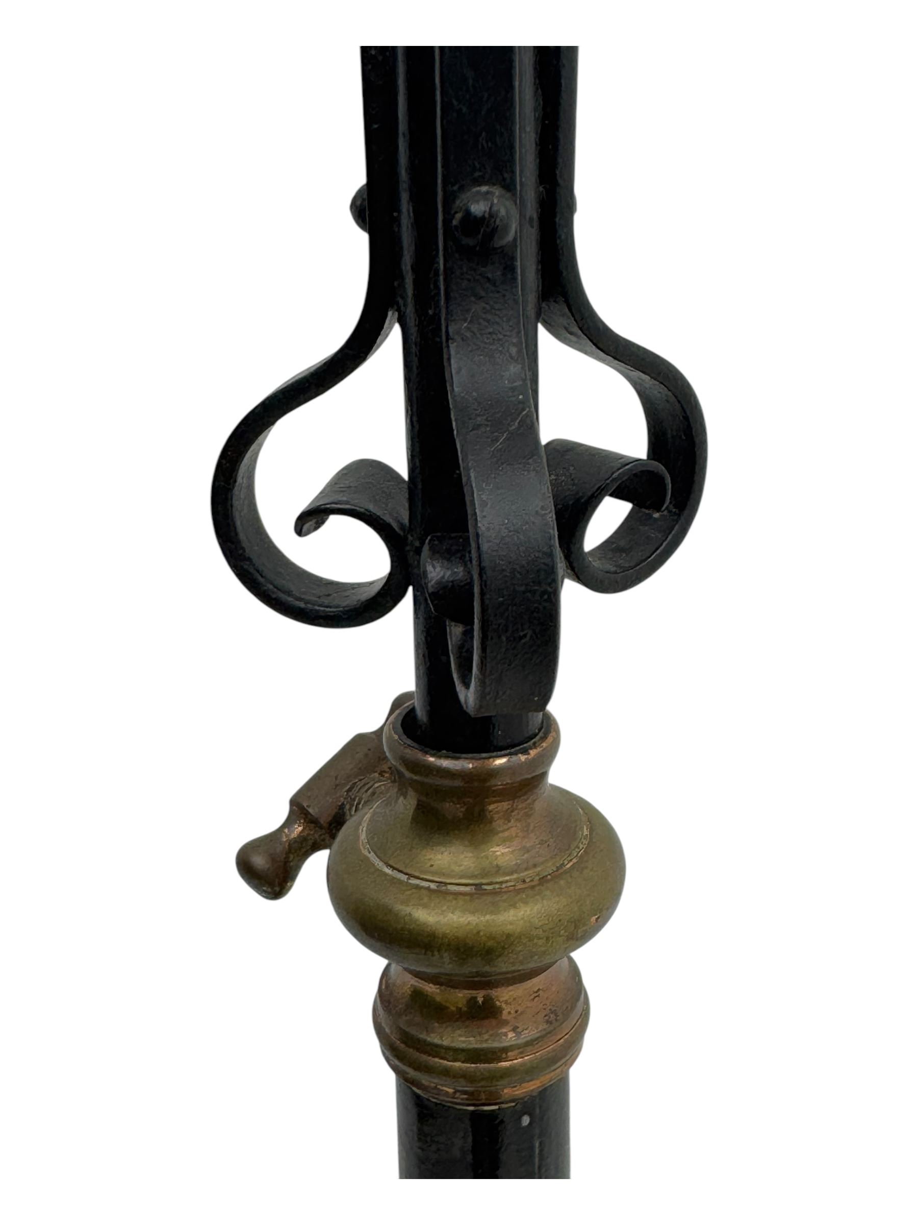 Late 19th century wrought iron and brass pulpit lamp, featuring an adjustable stem with a spiral twist detail, brass foliate mounts, and a tripod base with scrolled feet and decorative floral accents