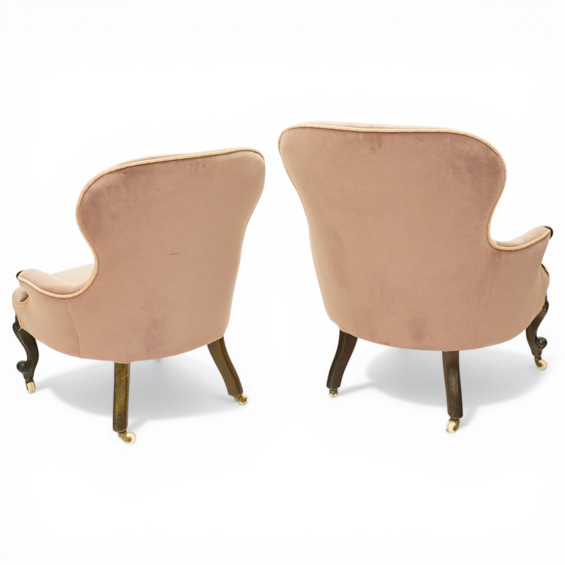 Pair of Victorian mahogany framed salon armchairs, spoon-back and sprung seat upholstered in buttoned lavender velour fabric with pink piping, shaped apron on cabriole legs with scroll feet and ceramic castors