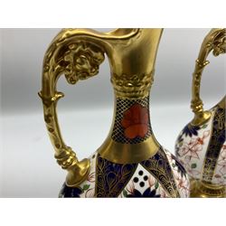 Pair of mid 20th century Royal Crown Derby Imari 1128 pattern Kedleston ewers, each with gilt scroll handle and neck, upon a gilt quatrefoil foot, each with printed marks beneath, H25.5cm