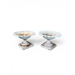 Coalbrookdale - pair of 19th century cast iron petal rim urns, squat form on square plinth, finished in distressed white paint, design registration number 133334, first registered 19 september 1860, number 19 in the Coalbrookdale Castings Catalogue (see illustration)