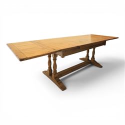 Traditional oak refectory dining table, fitted with draw leaves to either end extending to 257cm, on twin turned and block supports united by a stretcher, terminating in shaped trestle feet
