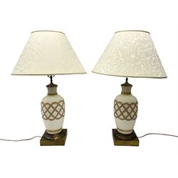 Pair of milk glass lamps of baluster form, decorated with gilded lattice panel raised upon brushed metal raised plinth, with patterned cream fabric shades, approx H78cm