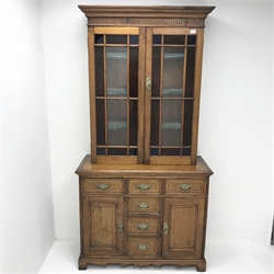 Edwardian oak bookcase on cupboard, two stained glass doors enclosing three shelves above six drawers and two cupboards, shaped plinth base, W106cm, H205cm, D44cm