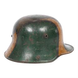 WWI German camouflage M17 helmet, with camouflage painted finish to the skull in green, brown and ochre colours with black separation lines, the interior with leather band which supports three pad leather lining, the pads stamped with indistinct marks 