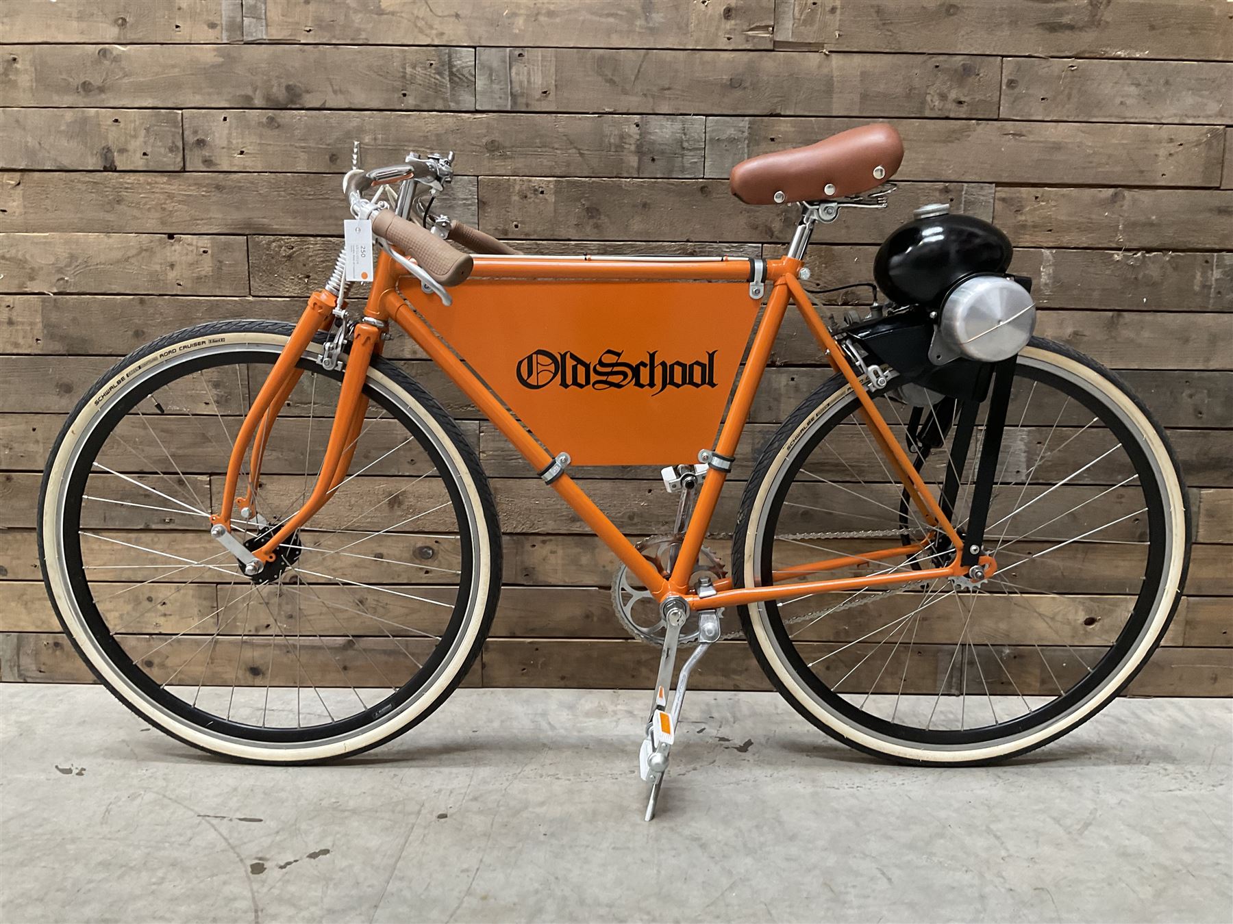 Fully restored vintage advertising bicycle with 2 stroke petrol engine, orange frame, tan leather seat