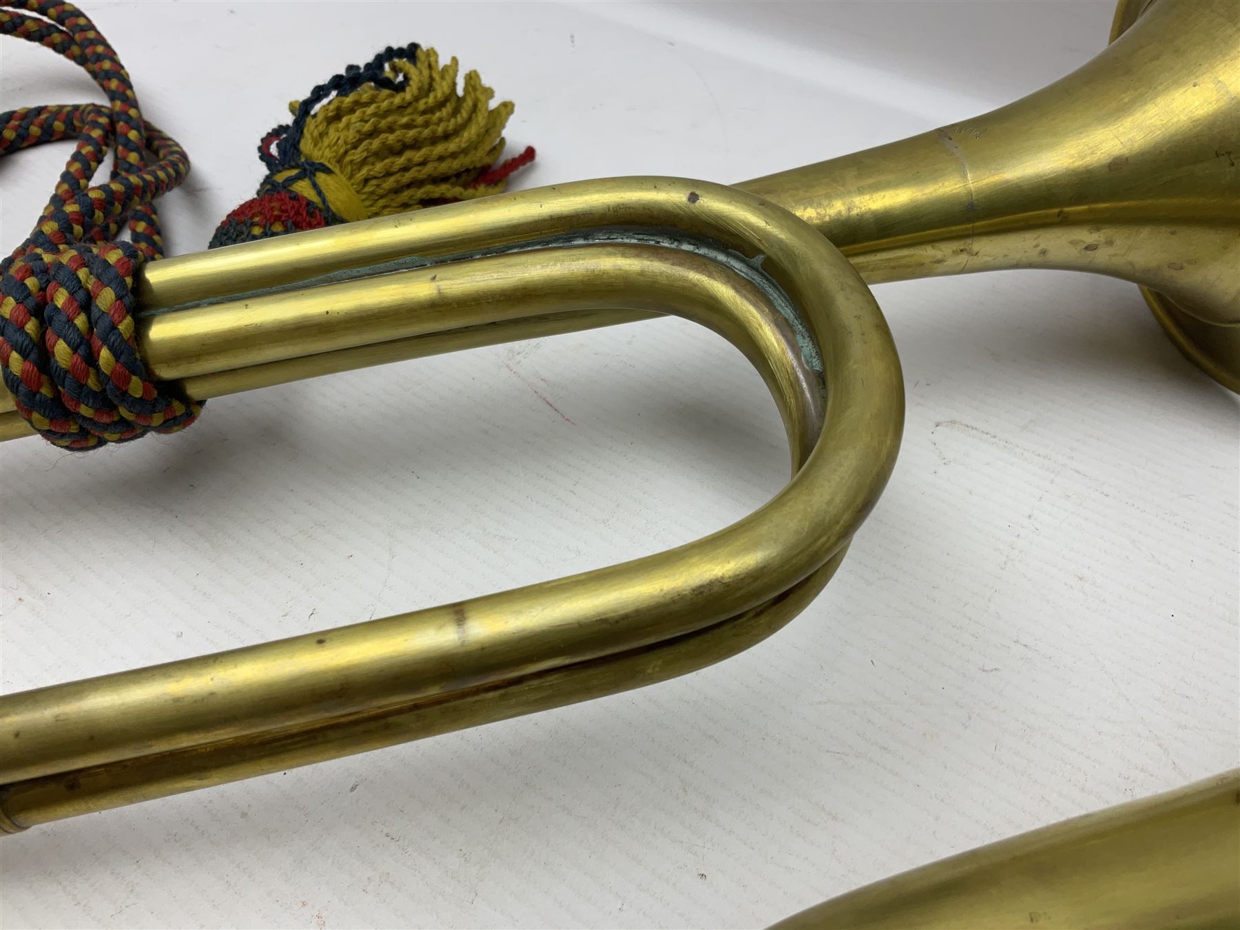 Two military brass bugles by Mayers and Harrison Ltd. Manchester each with crows foot mark and dated 1966; both with multi-coloured cord and tassels, longest 52.5cm (2)