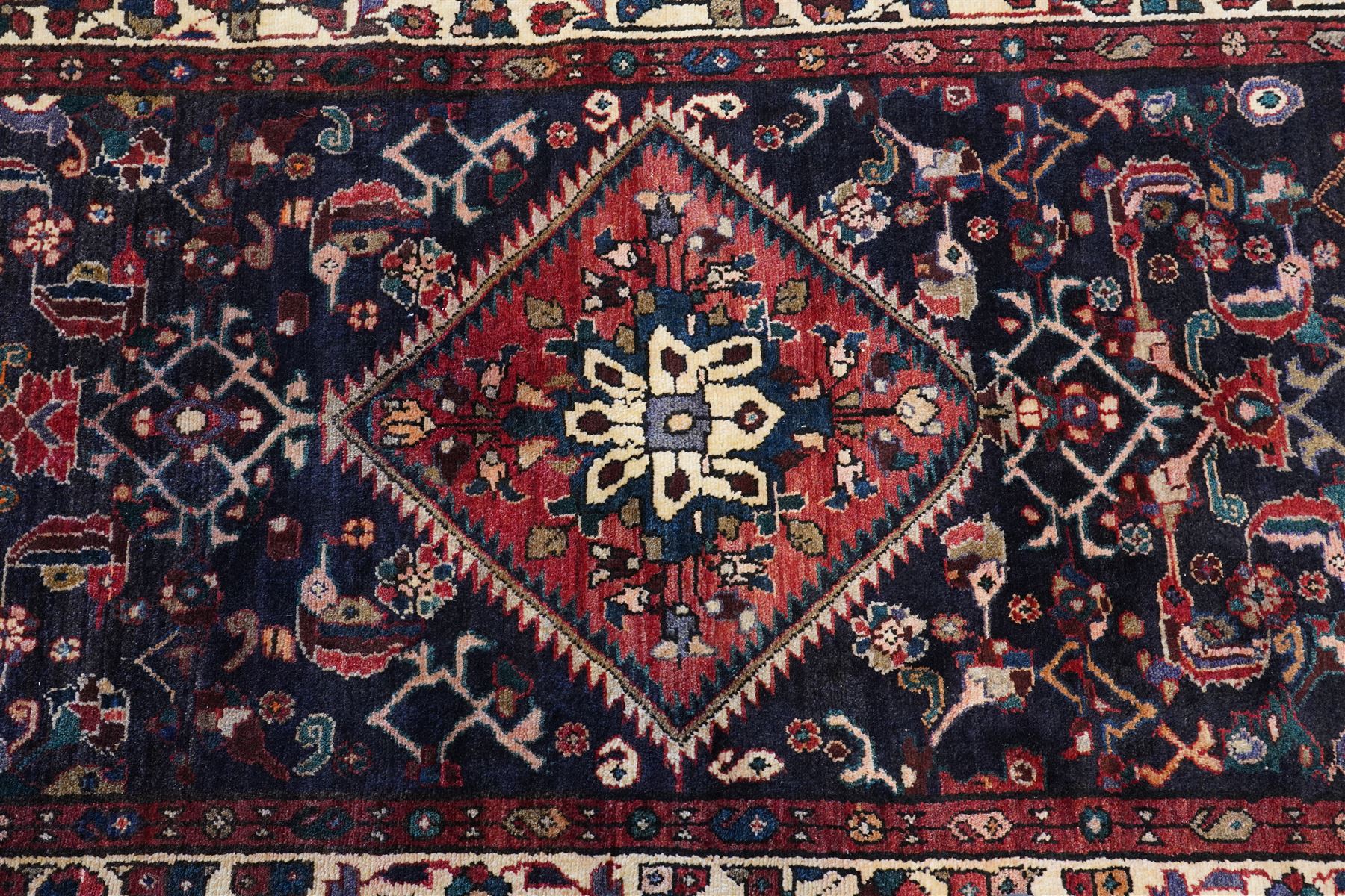 North West Persian Hamadan hand-knotted runner, indigo field with an all-over herati inspired lattice issuing from a central axis with stylized palmettes, rosettes and angular vinery, enclosed by stepped triangular spandrels with ivory reserves, broad ivory main border of stylized flowers and geometric devices, flanked by reciprocal guard stripes, cotton fringe ends 