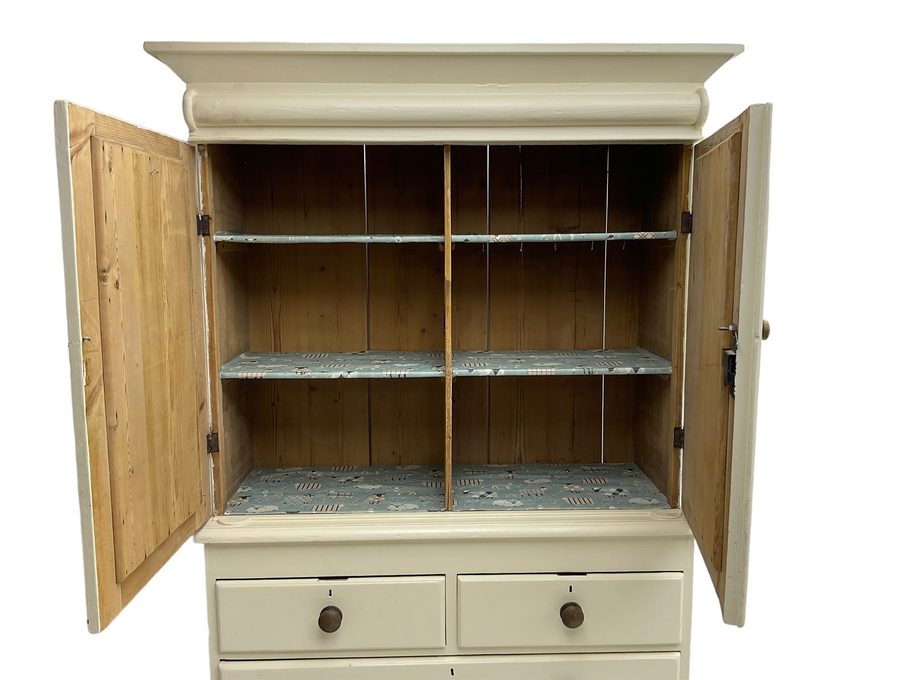 Victorian cream painted pine cupboard-on-chest or housekeeper's cupboard, projecting cornice over two double-arch panelled cupboard doors enclosing two shelves, flanked by spiral turned uprights, base fitted with two short over two long drawers, on bun feet