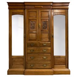 Edwardian walnut combination breakfront triple wardrobe, projecting cornice over cushioned and fluted frieze, central fielded panelled cupboard carved with foliate decoration above two short and three long drawers, flanked by two bevelled mirror doors enclosing hanging hooks with single drawers to base, retailed by J Tonks & Sons, Scarborough
