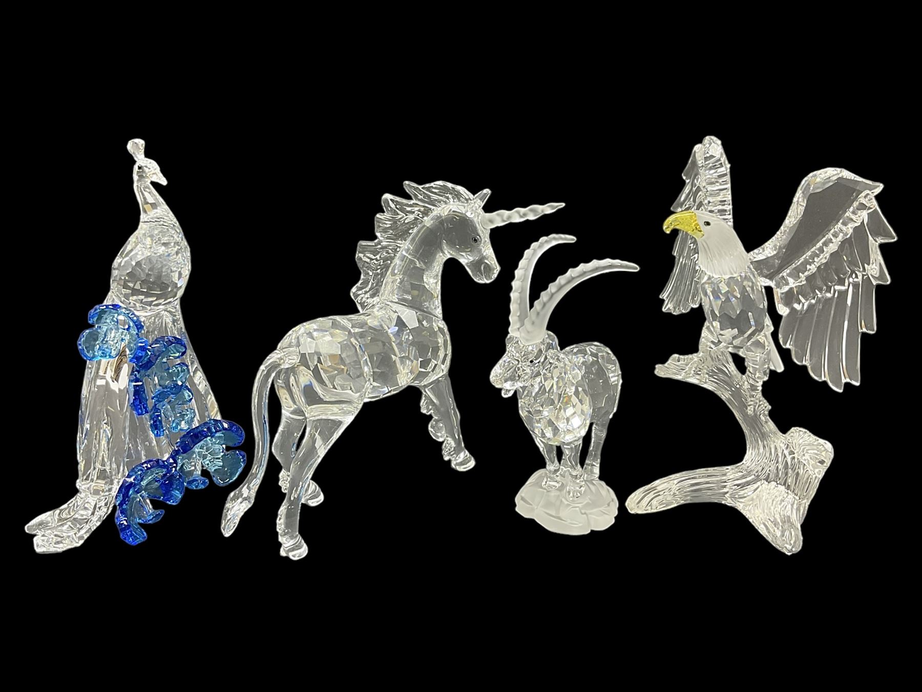 Swarovski Crystal animals, comprising white peacock, the tail with cascading blue flowers, perched eagle with yellow beak, ibex with frosted crystal horns and unicorn with frosted crystal horn, tallest H13cm