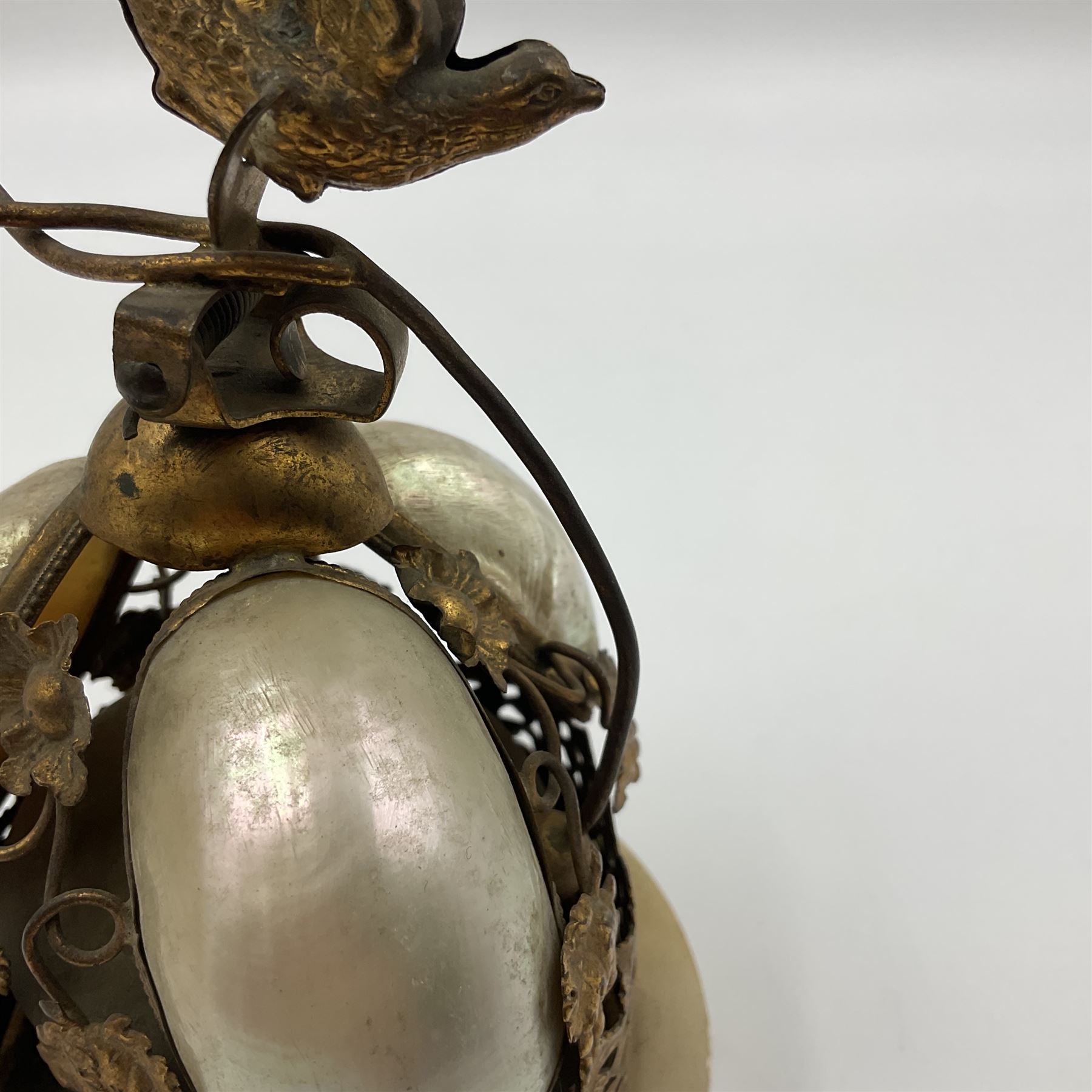 Victorian evening dinner bell, with three mother of pearl shells, floral and grape gilt decoration, and bird finial, raised upon a circular soapstone base with gilt pierced gallery, H14cm