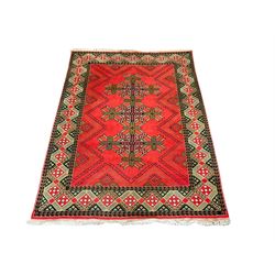 Red ground rug, the field decorated with triple geometric star motifs, repeating lozenge band border