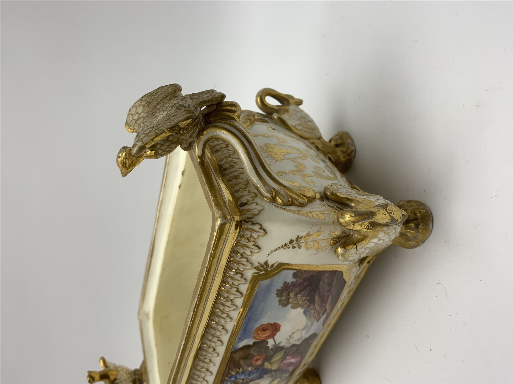 19th century Coalport bough pot, circa 1820, of bombe form, the body with twin handles surmounted by two birds and raised upon four feet modelled as swans, hand painted with two panels depicting an urn of flowers set against a mountainous landscape, the whole heightened in gilt throughout, H13cm L21cm