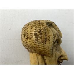 19th century carved ivory walking cane handle, modelled as the head of a greyhound with inset glass eyes, together with a further 19th century ivory example, modelled as a caricature of a gentleman's head, (2)