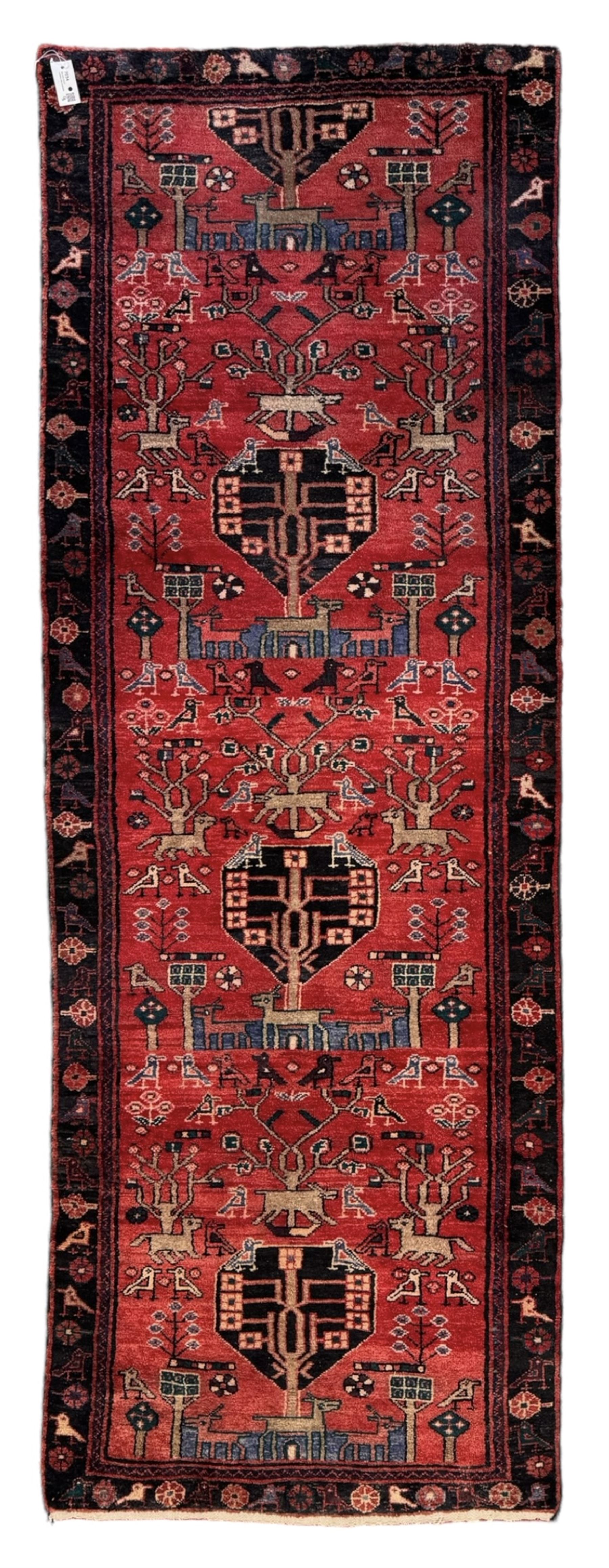 Persian crimson ground runner, the field decorated with stylised tree and animal motifs, indigo ground border decorated with alternating stylised flowerhead and bird motifs 