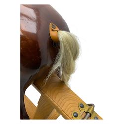 Contemporary carved wooden rocking horse, with leather saddle and bridle, horsehair mane and tail, raised on a pine stand with swing iron supports