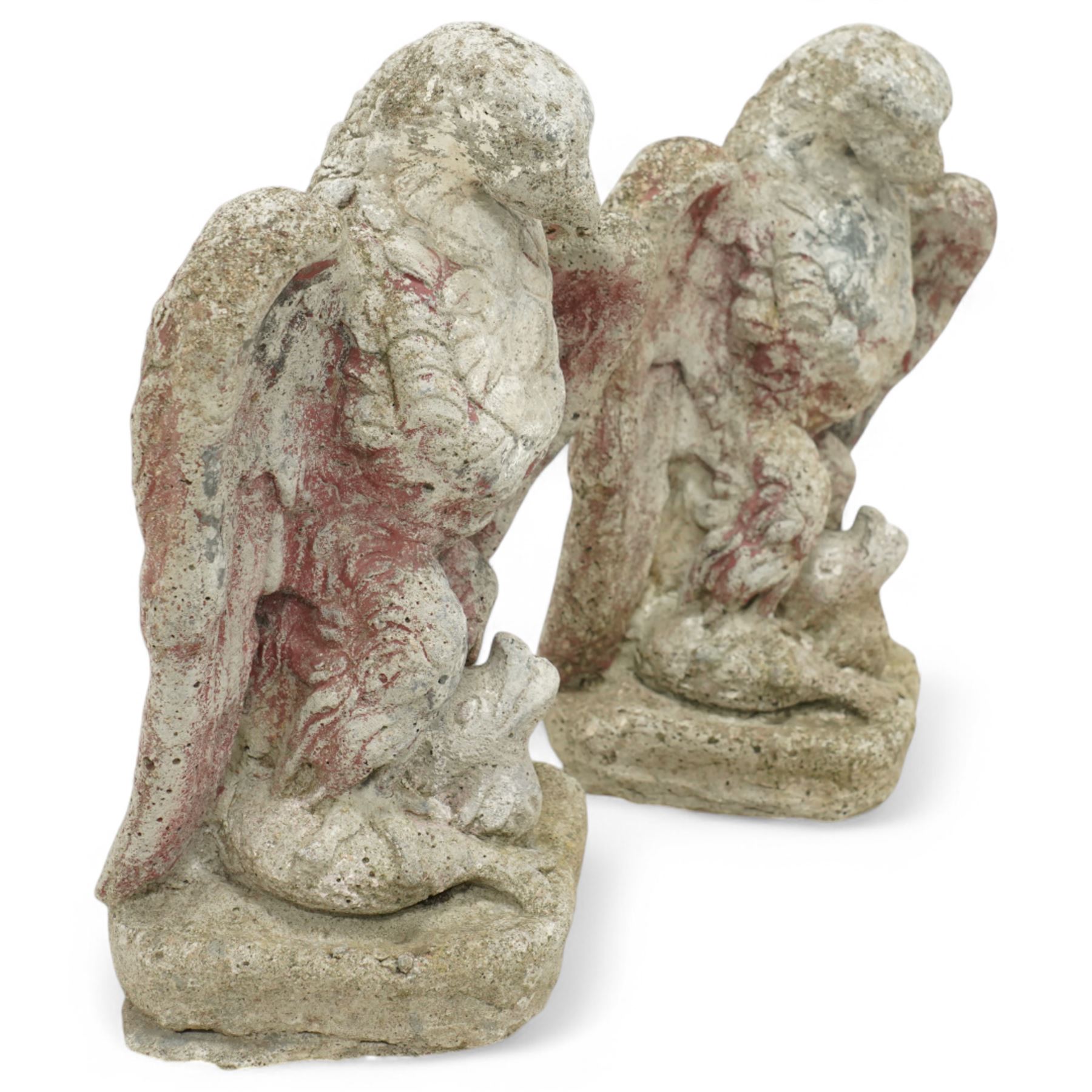 Pair of early 20th century painted stoneware eagle figures, modelled with wings partially spread and talons gripping prey, on a stone plinth