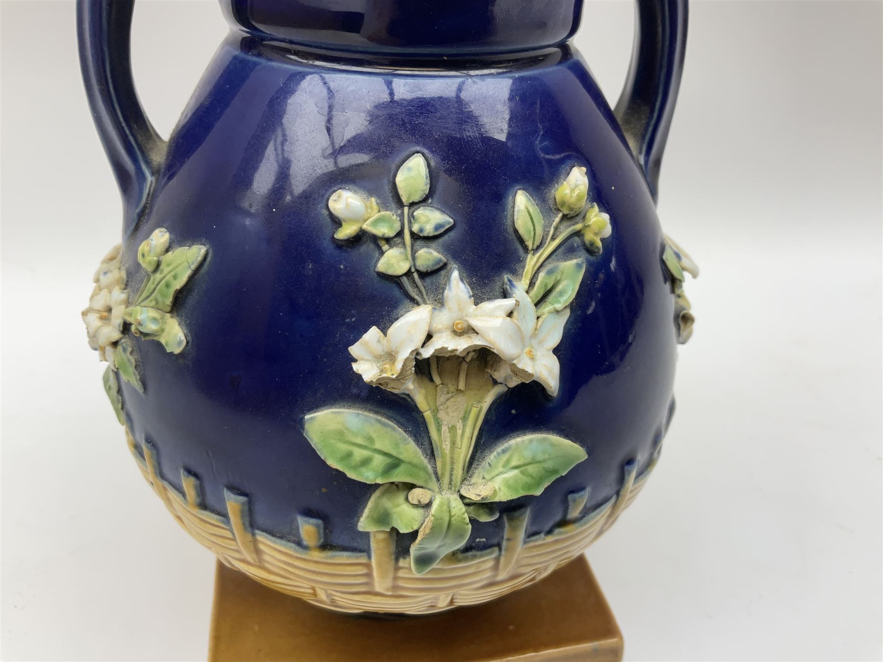 Minton majolica vase, the squat body with twin handles, with part osier moulding and applied Spring flowers against a cobalt blue ground, upon integral square base, impressed beneath Minton 1316, H16.5cm