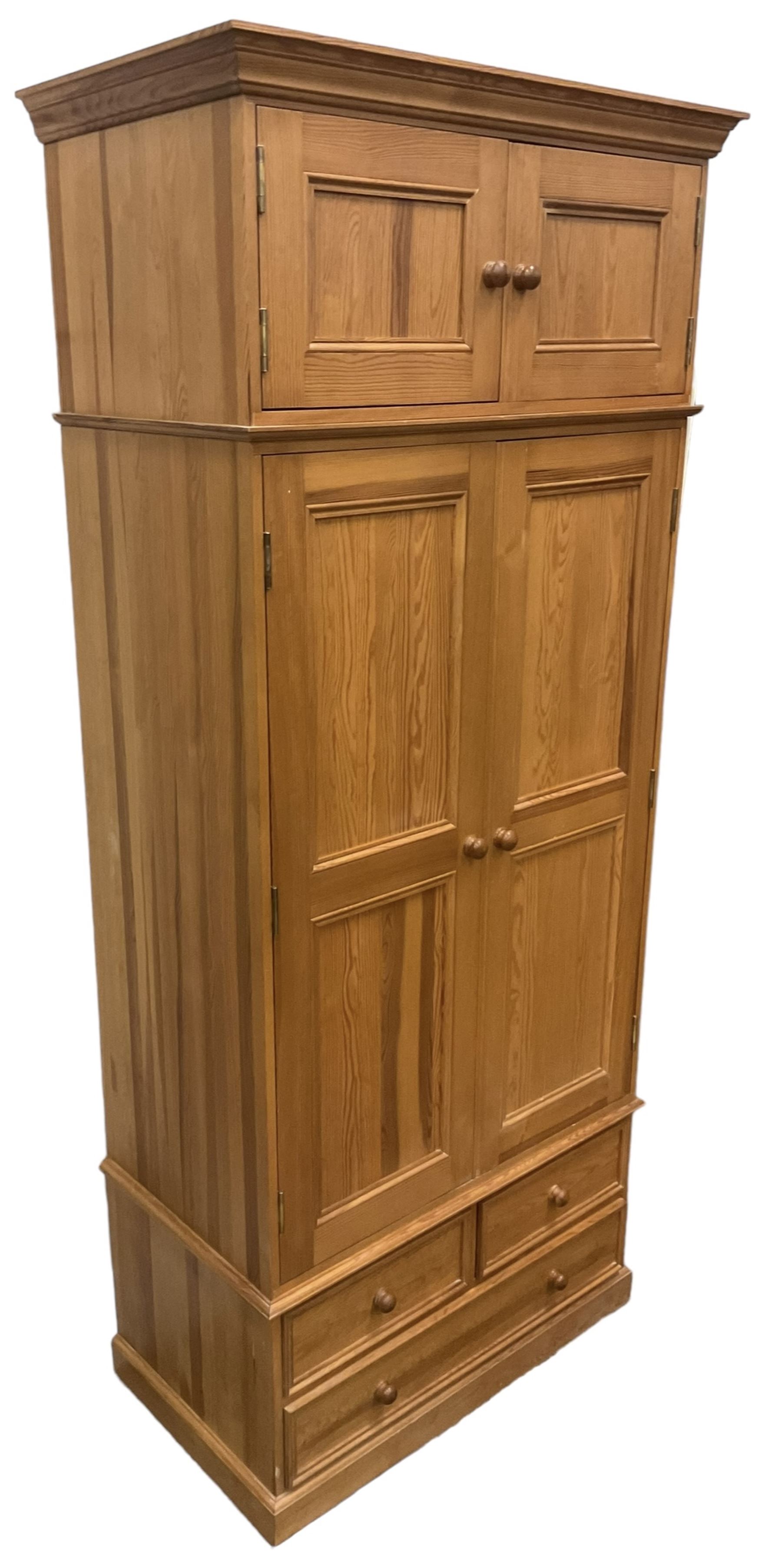 Solid pine double wardrobe, fitted with top box, enclosed by panelled doors, two short and one long drawer, on plinth base 