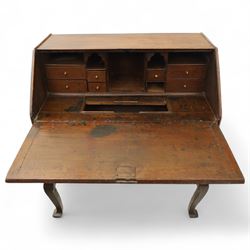 Early 18th century George I oak bureau on original stand, the fall front enclosing an arrangement of correspondence drawers and pigeonholes over central well, fitted with single long drawer below, the shaped apron over cabriole supports with pad feet