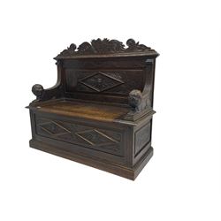 Late 19th century heavily carved oak monks bench, scroll carved pediment with central anthemion motif, panelled back with lozenge and carved green man mask, down swept arms in form of recumbent lions flanking hinged box seat, panelled base carved with masks and scrolls on moulded skirt