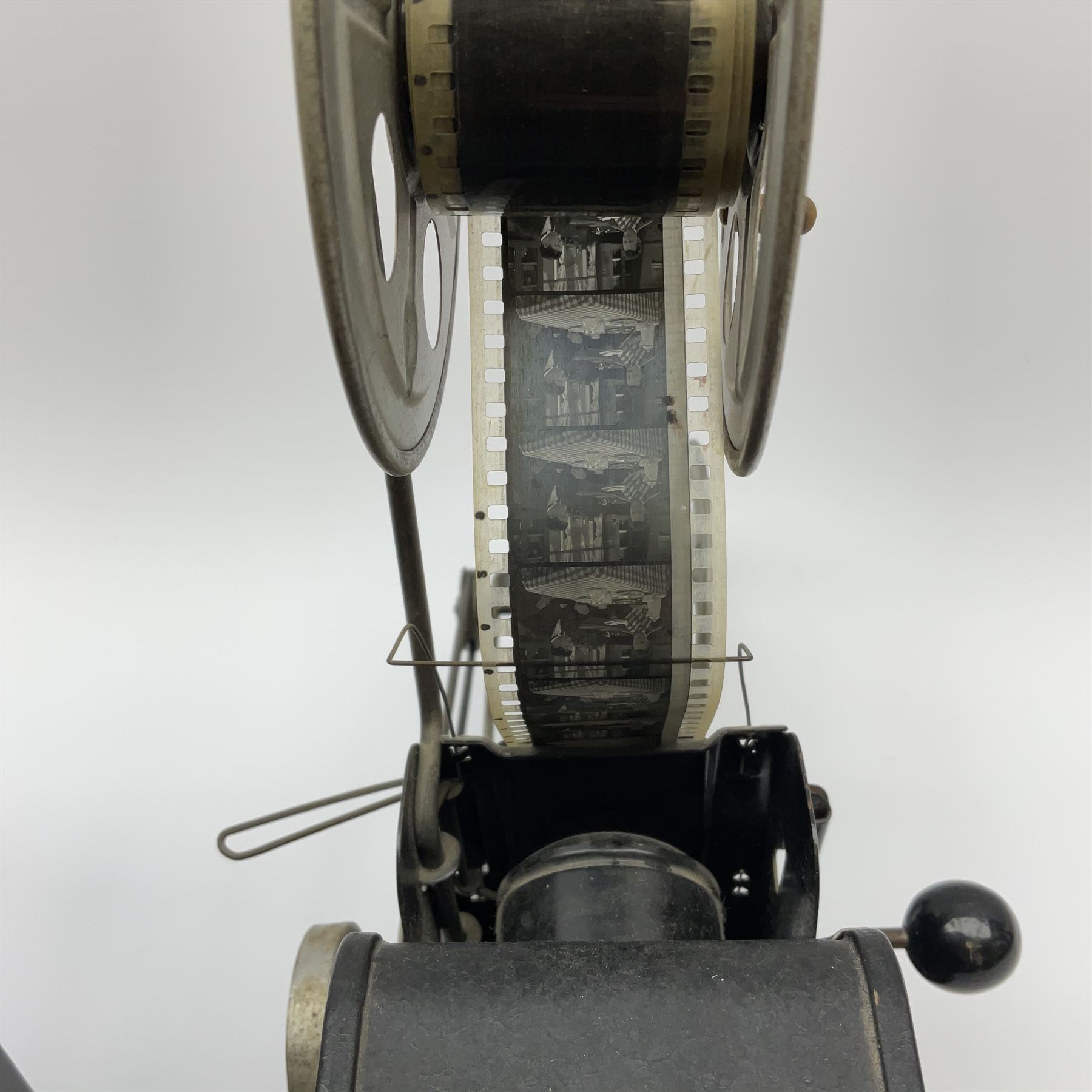 Early 20th century tinplate combined magic lantern and 35mm cinematograph projector, hand-cranked, with electric bayonet lamp, fitted with film reels, L35cm overall, and a similar projector by Gebruder Bing Nuremberg with spirit lamp (glass chimney a/f) L22cm, with two reels of film 
