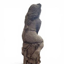 Pair of weathered composite stone garden figures, modelled as a girl and a young satyr playing the panpipes seated on column supports, the fluted columns with climbing ivy vines and surmounted animal, butterfly and other zoomorphic motifs