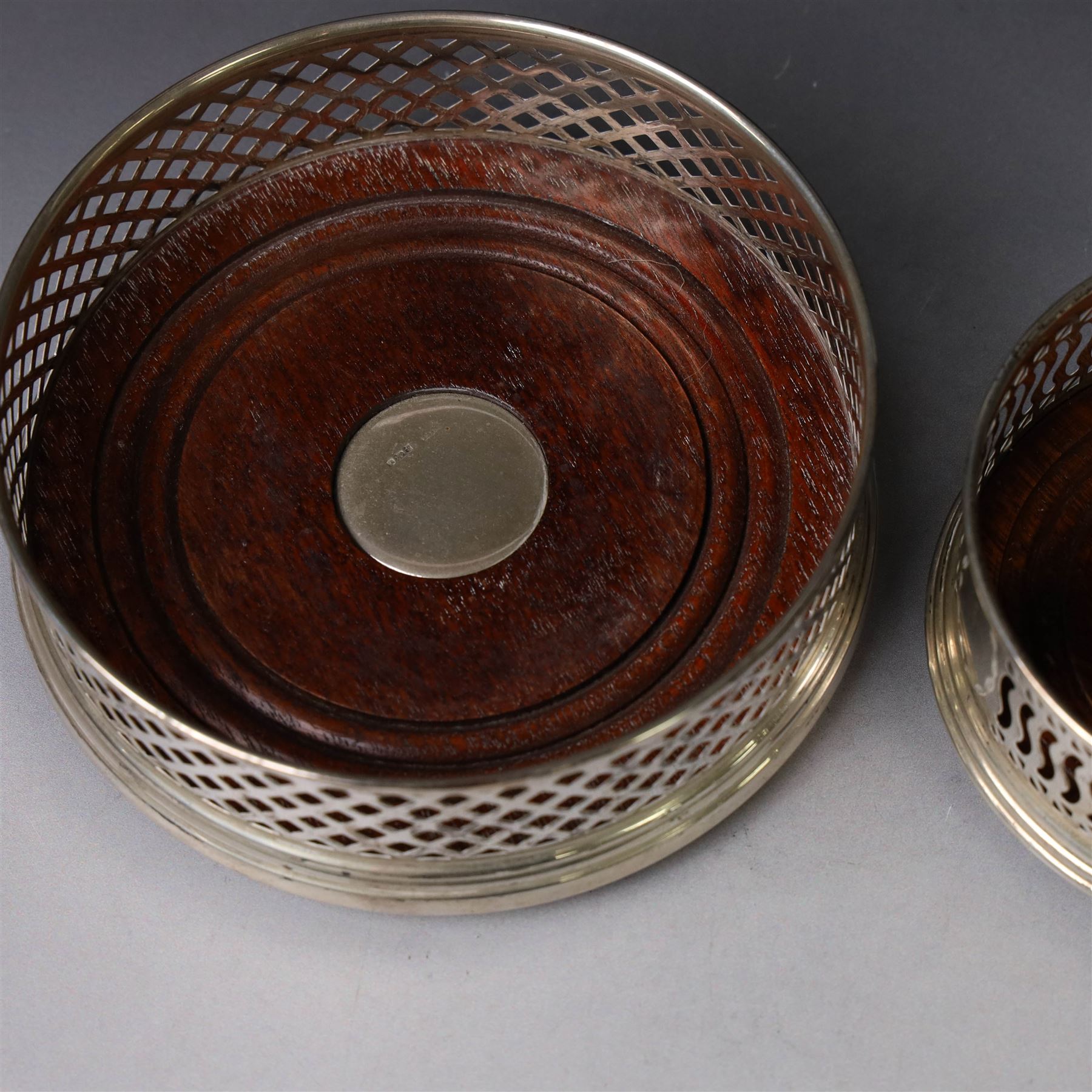 Two silver mounted bottle coasters, the larger example with latticework sides, hallmarked Mappin & Webb Ltd, Birmingham 1993, the smaller example with pierced sides, hallmarked W I Broadway & Co, Birmingham 1998, largest D12cm