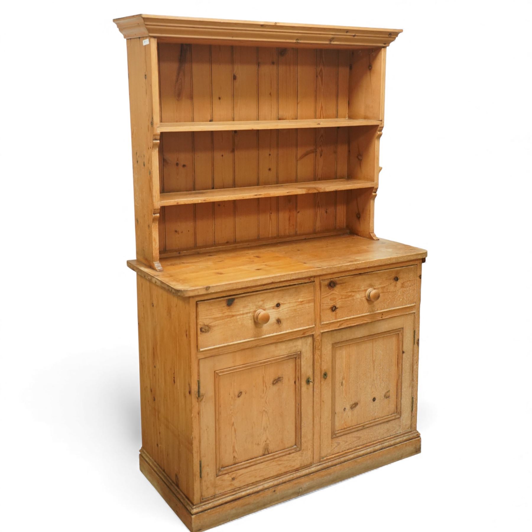 Traditional pine kitchen dresser, the open rack with three shelves beneath a moulded top, over a base fitted with two drawers and a pair of panelled cupboard doors, the whole raised on a moulded base