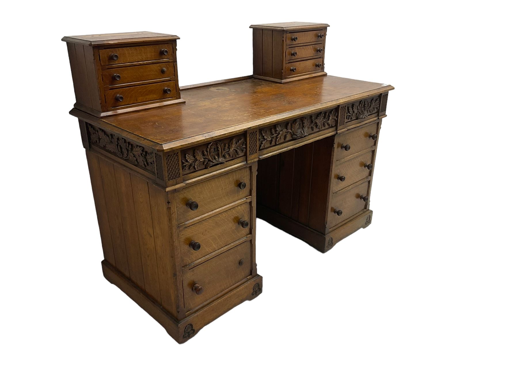 Late 19th century heavily carved oak twin pedestal desk, rectangular top with two raised trinket or correspondence structures each with three drawers, rectangular top over three frieze drawers carved with acorn and oak leaf decoration, each pedestal with three drawers with acorn husk shaped handles