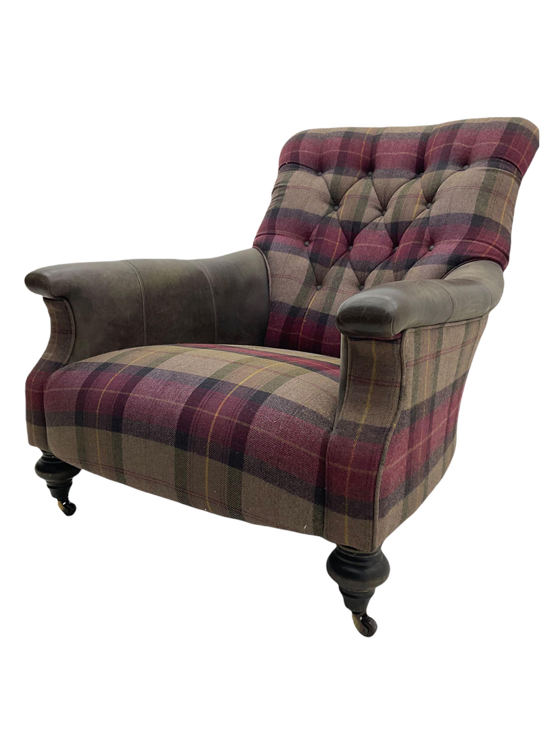 John Sankey - low armchair, buttoned back upholstered in tartan patterned fabric with contrasting grey leather, raised on turned and ebonised front feet with brass and ceramic castors, with matching foot stool