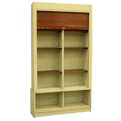 Large early 20th century pine cabinet with tambour front enclosing six adjustable shelves above two open cupboards, plinth base